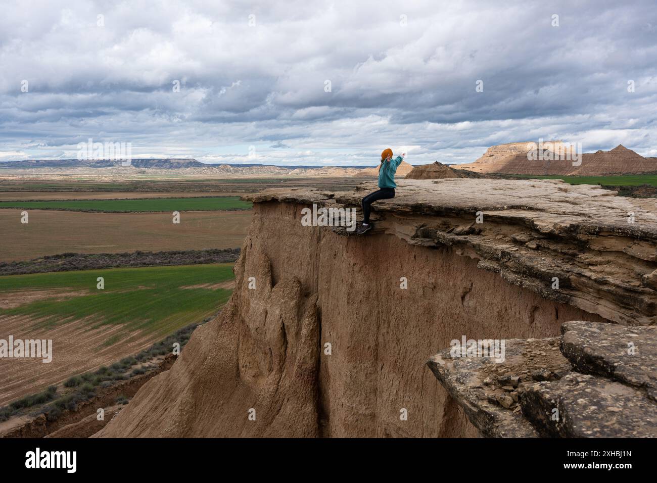 Donna a braccia aperte seduta su scogliere rocciose. Donna che sente la libertà Foto Stock