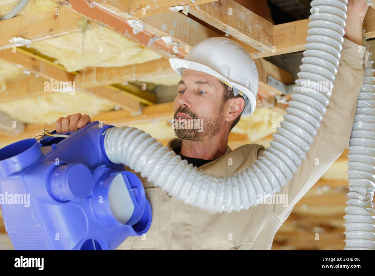 appaltatore maschio che installa il sistema di ventilazione in una proprietà in fase di ristrutturazione Foto Stock