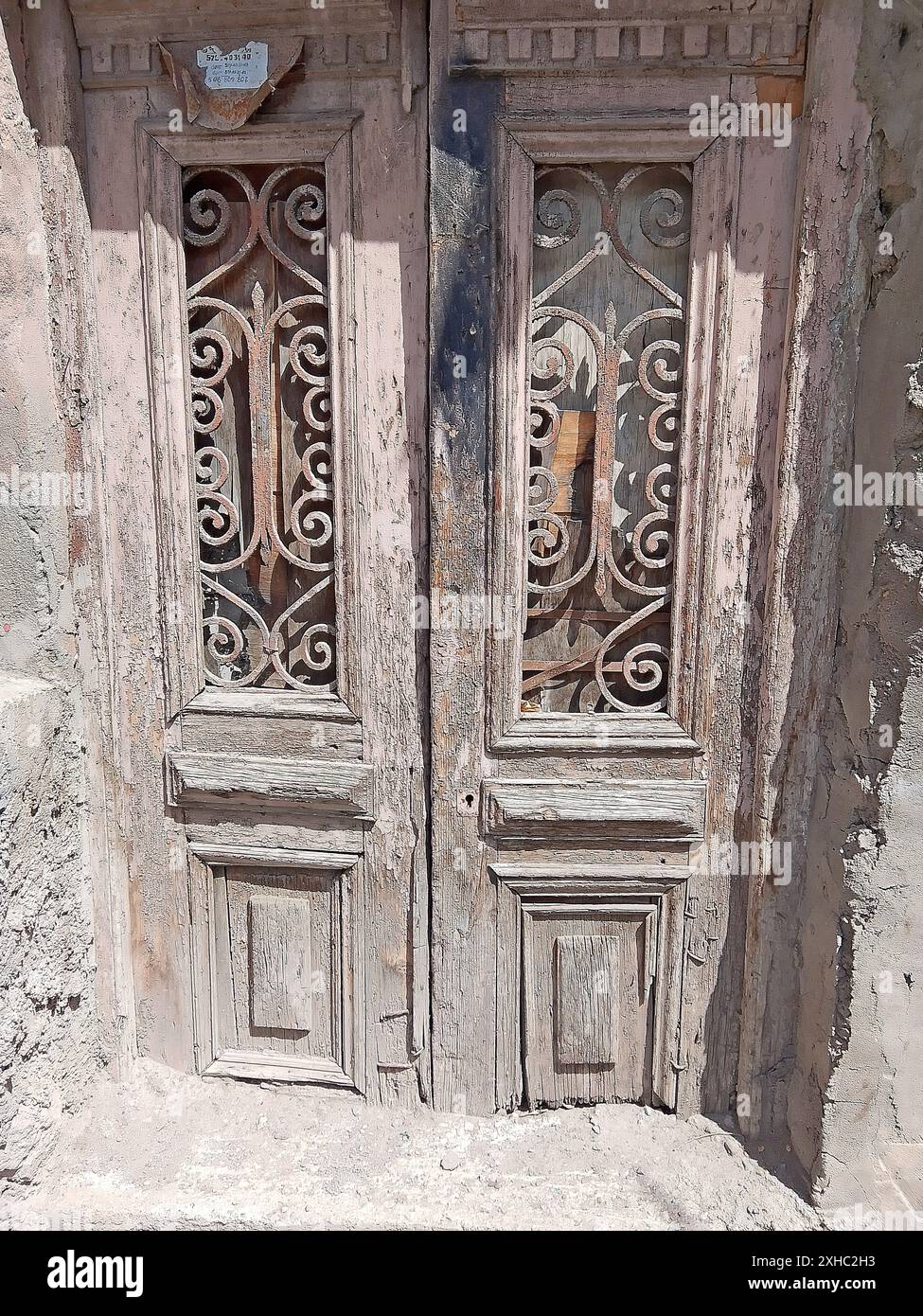 Una porta di legno intemprata con lavorazioni in metallo ornato e vernice sbucciante, che mostra la storica architettura europea. Ideale per arredi vintage, architettura Foto Stock