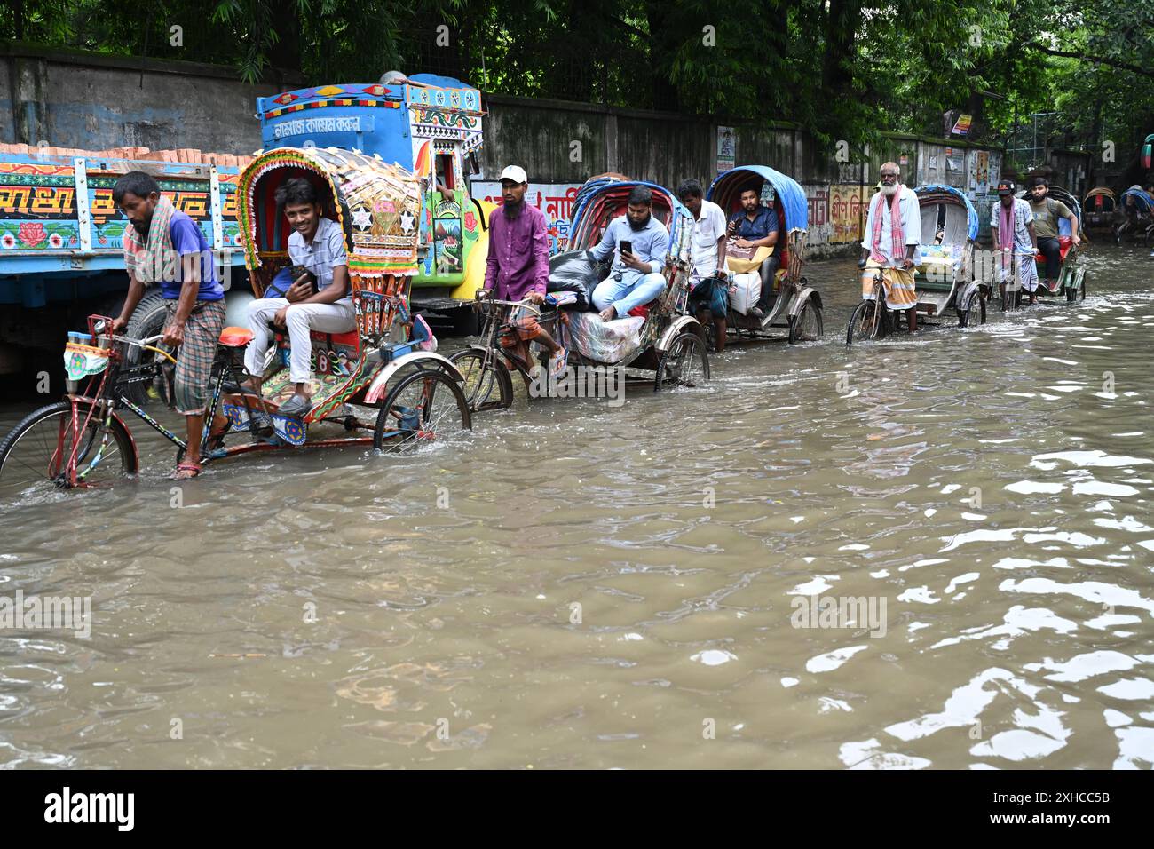 Persone e veicoli che cercano di muoversi attraverso la strada bagnata di Dacca, Bangladesh, il 26 luglio 2024 Foto Stock