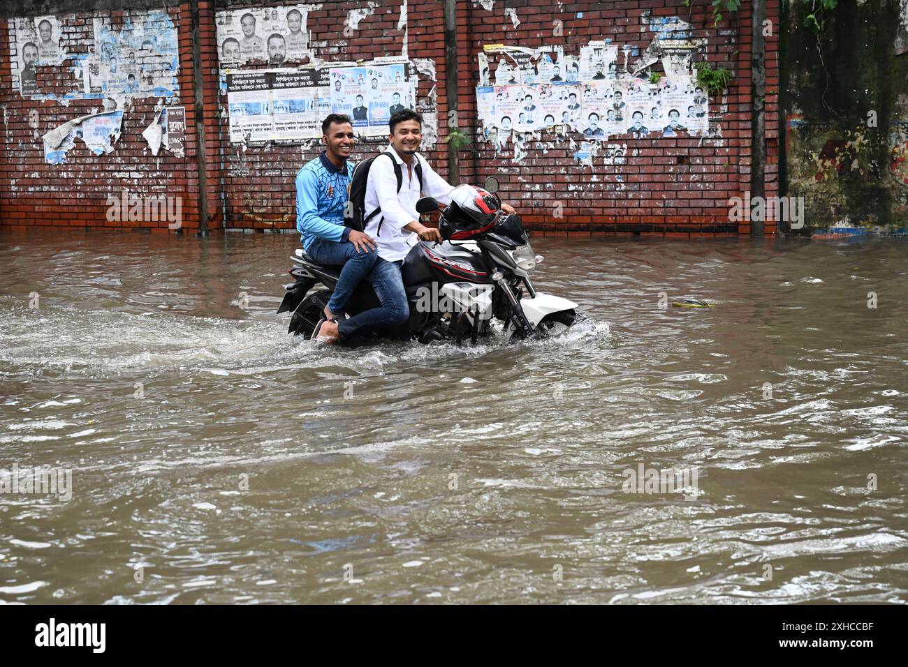 Persone e veicoli che cercano di muoversi attraverso la strada bagnata di Dacca, Bangladesh, il 26 luglio 2024 Foto Stock
