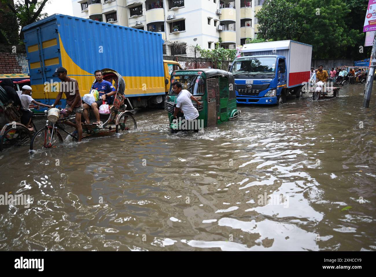 Persone e veicoli che cercano di muoversi attraverso la strada bagnata di Dacca, Bangladesh, il 26 luglio 2024 Foto Stock