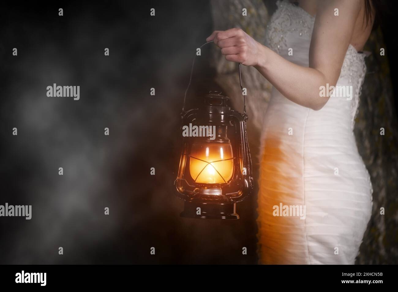 Donna irriconoscibile con Lanterna d'epoca fuori di notte. Giovane donna in bianco abito lungo che cammina in legno di notte. Foto di alta qualità Foto Stock