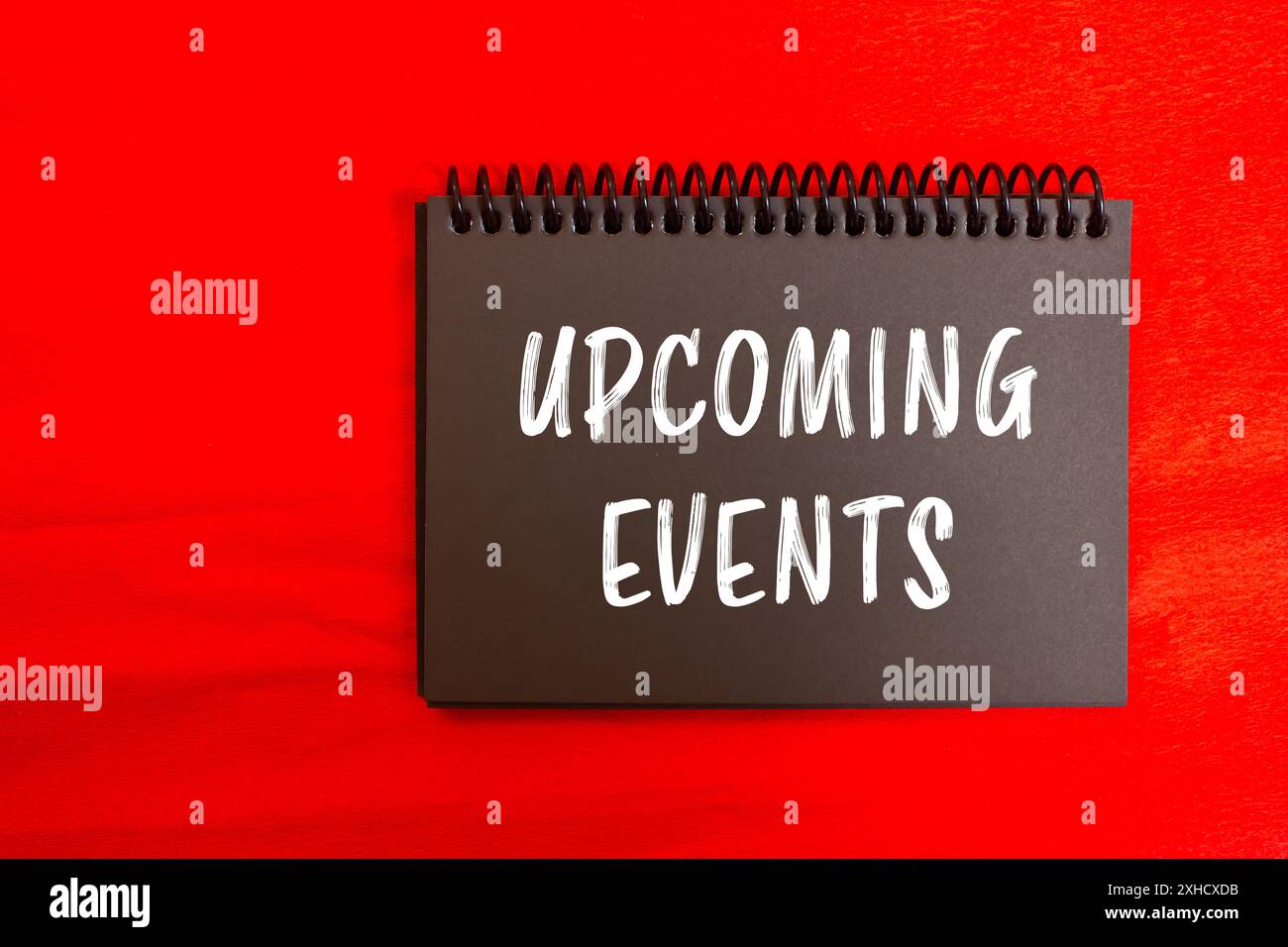 Messaggio relativo agli eventi in programma scritto su una pagina nera del notebook con sfondo rosso. Simbolo degli eventi concettuali imminenti. Copia spazio. Foto Stock