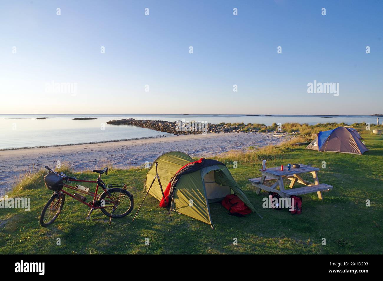 Campeggio su una spiaggia tranquilla al crepuscolo con tenda, bicicletta e tavolo da picnic, vacanze in bicicletta, vacanze avventurose, Bleik, Vesteralen, Langoya, Nordland, Norvegia Foto Stock