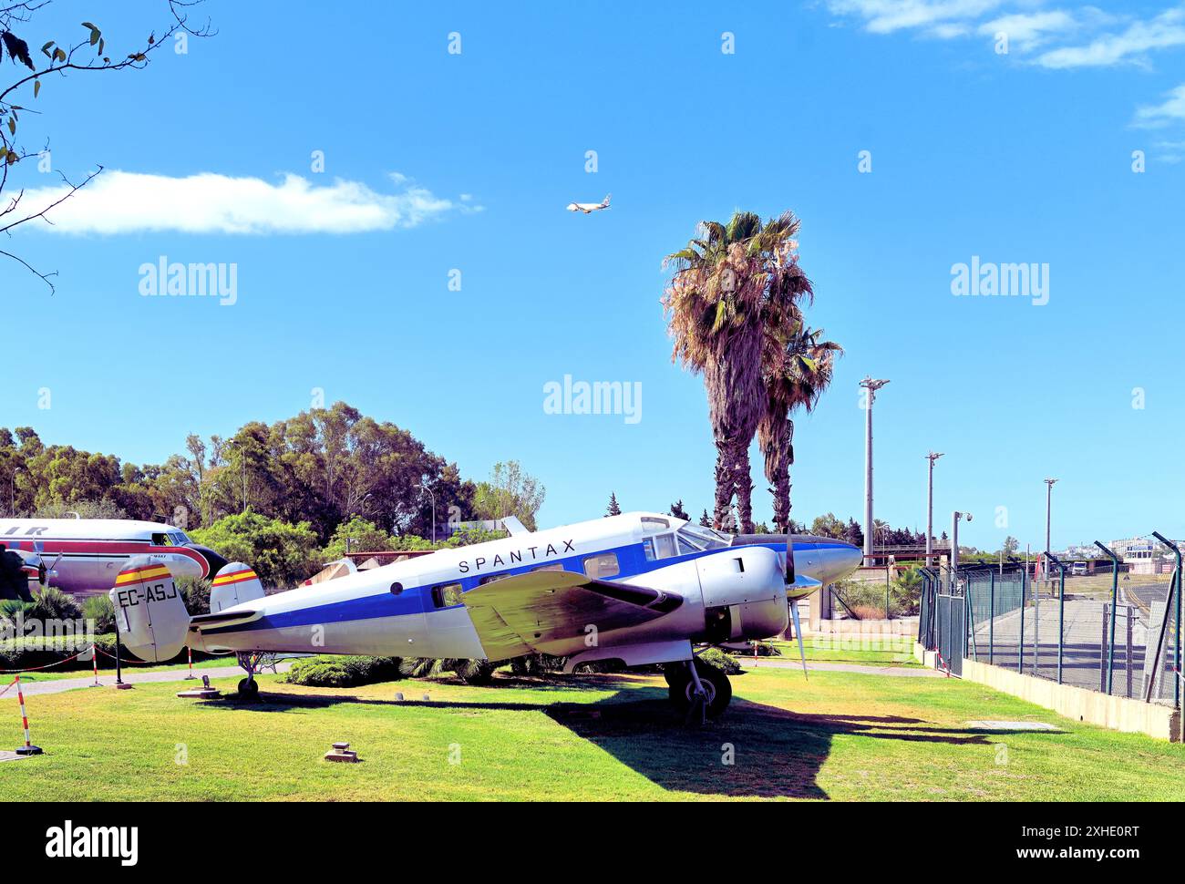 Malaga Aero Museum Aeromuseo e un Beechcraft 18 che si affaccia sul grembiule dell'aereo con un jet passeggeri appena decollato sullo sfondo del cielo blu Foto Stock