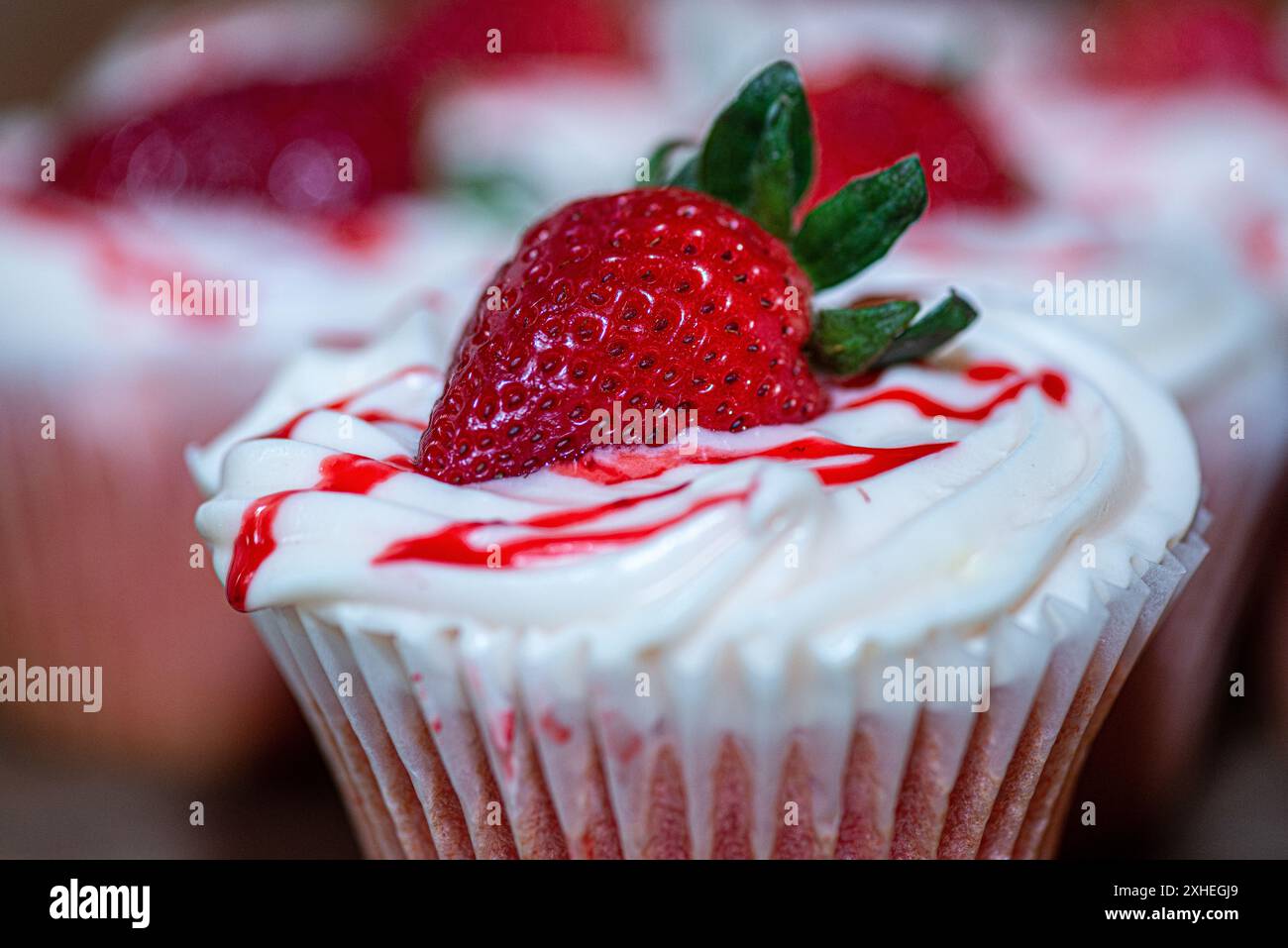 Deliziosi cupcake alle fragole con glassa alla vaniglia e fette di fragole Foto Stock