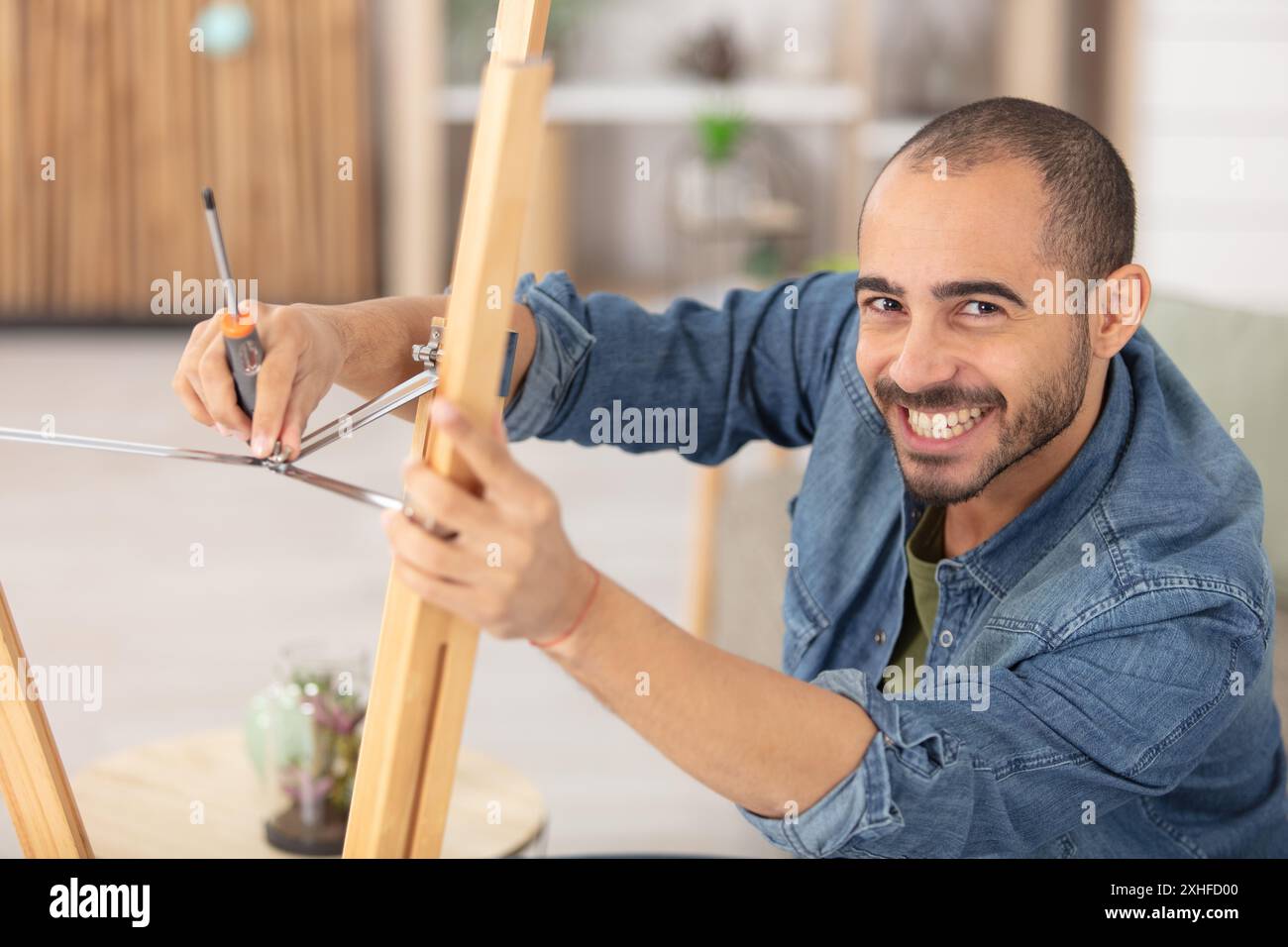 l'artigiano assembla le gambe del treppiede di una lampada in legno Foto Stock
