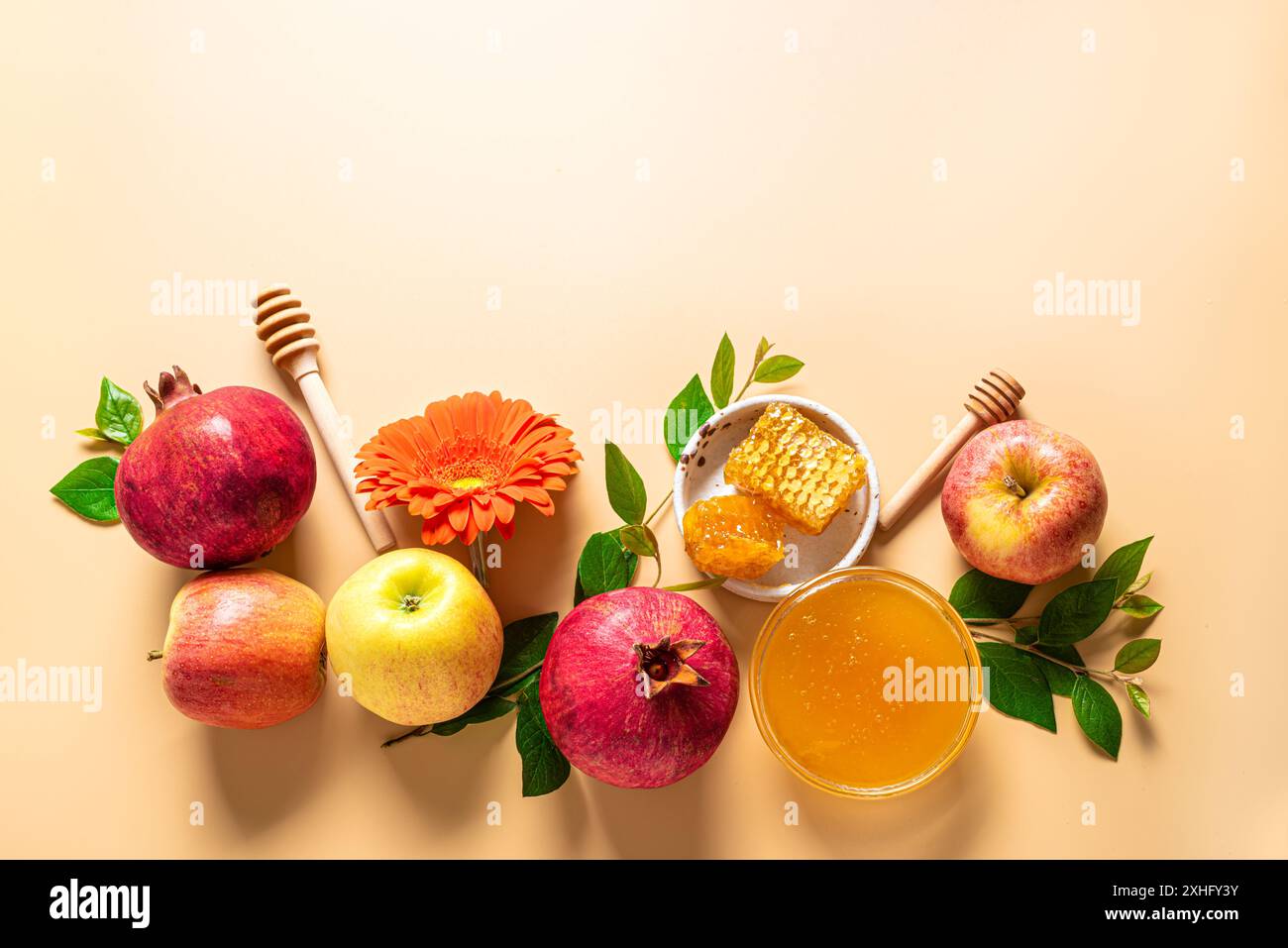 Rosh Hashanah, allestimento creativo per le vacanze del capodanno ebraico. Modello di biglietto d'auguri con simboli tradizionali: Mele, miele, melograno e fiori sul beige Foto Stock