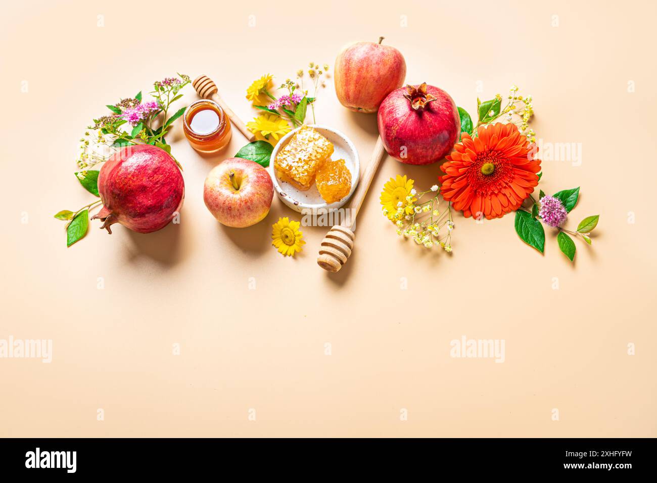 Rosh Hashanah concetto di vacanza per il Capodanno ebraico. Design creativo di simboli tradizionali - mele, miele, melograno e fiori su sfondo arancione beige Foto Stock