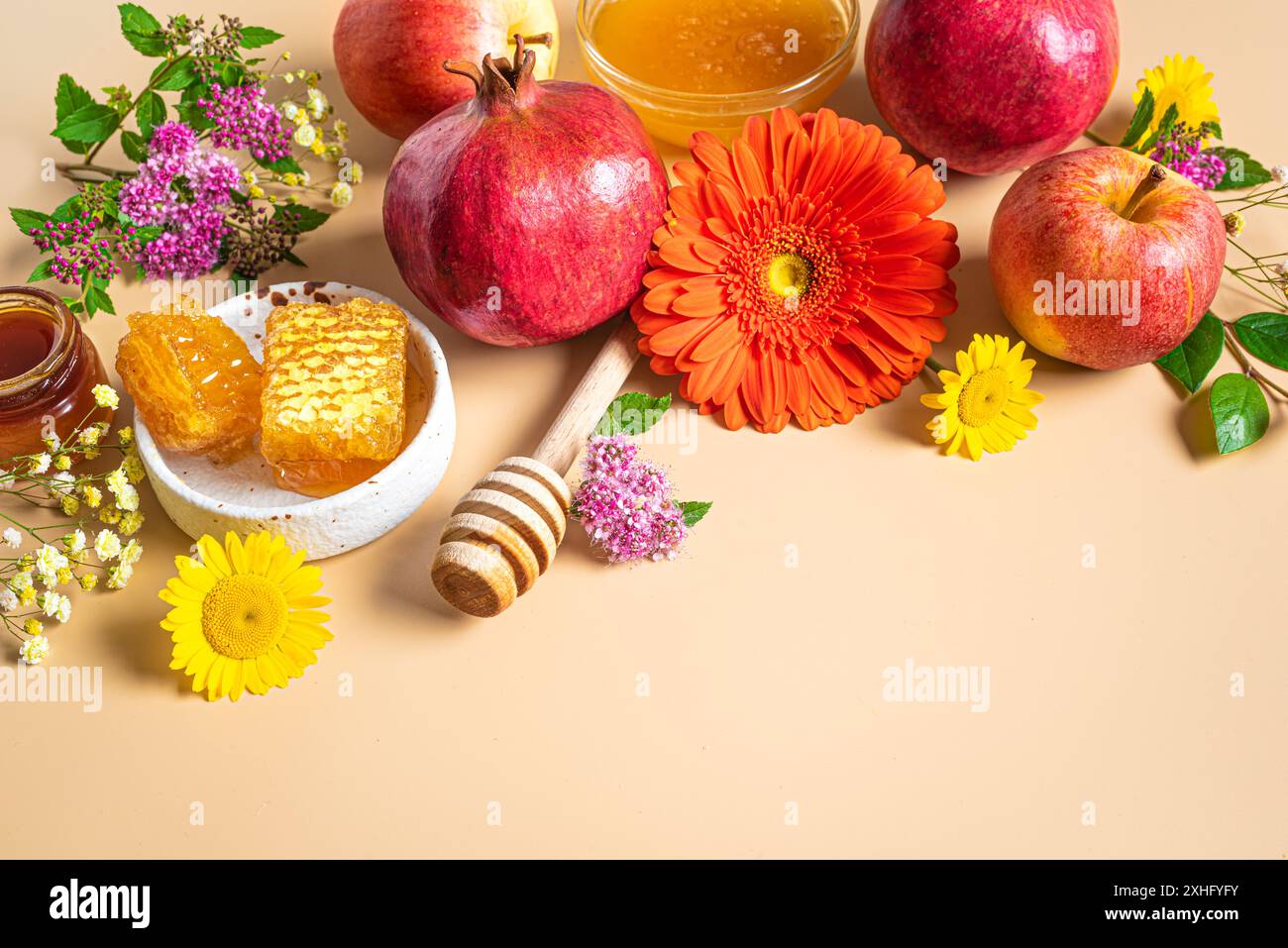 Rosh Hashanah (festività del capodanno ebraico). Simboli tradizionali: Melograno, mele, miele e fiori su sfondo arancio beige vicino Foto Stock