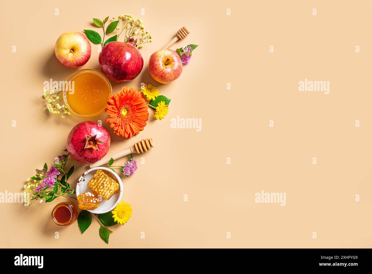 Rosh Hashanah (festività del capodanno ebraico). Simboli tradizionali: Melograno, mele, miele e fiori su sfondo beige, spazio copia. H Foto Stock