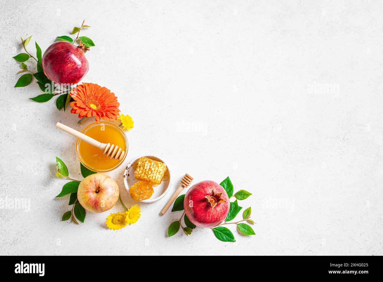 Rosh Hashanah concetto di vacanza per il Capodanno ebraico. Layout creativo dei simboli tradizionali: Mele, miele, melograno e fiori su controbattitore bianco Foto Stock