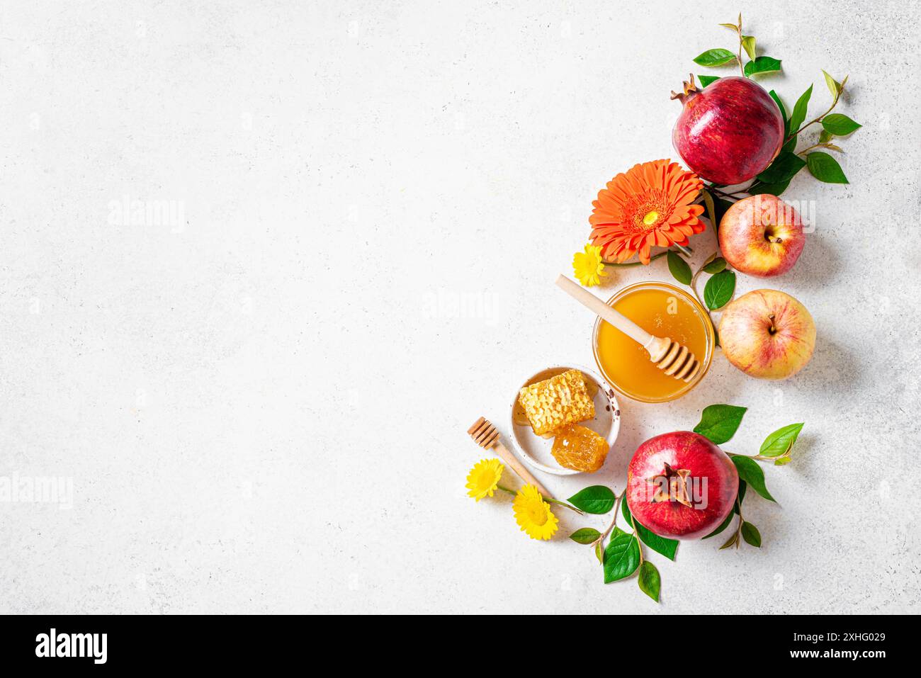 Rosh Hashanah concetto di vacanza per il Capodanno ebraico. Layout creativo di simboli religiosi tradizionali: Mele, miele, melograno e fiori su bianco Foto Stock