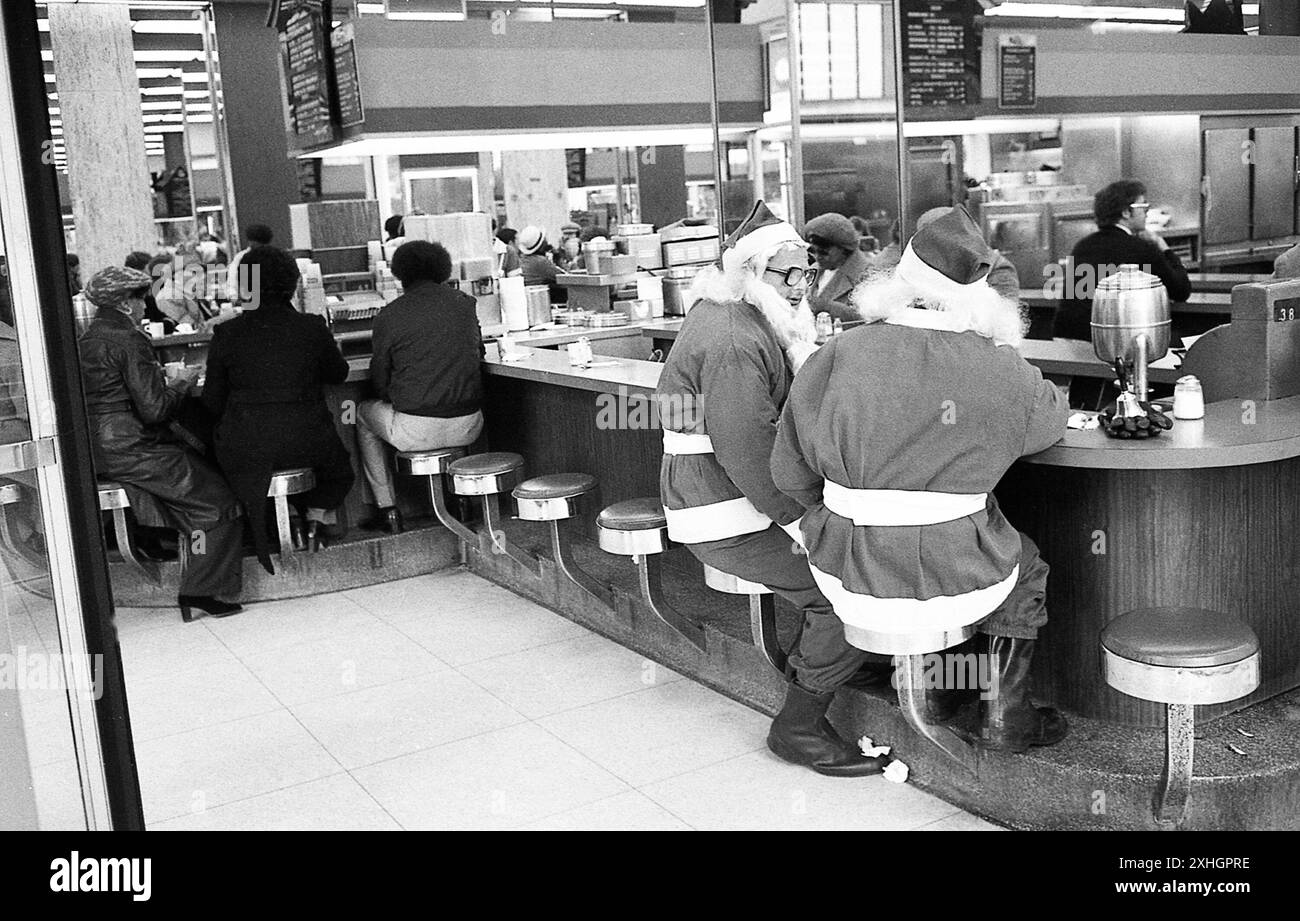 New York, NY, 1976: In una gastronomia a Manhattan, un paio di clausole di Babbo Natale dell'Esercito della salvezza si prendono una pausa dal stare in piedi lungo i marciapiedi chiedendo agli acquirenti di donazioni. Foto Stock