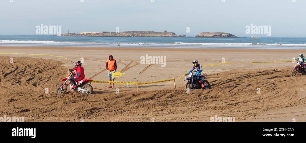 Gara di motocross sulla spiaggia con un'isola alle spalle all'orizzonte a Essaouira, Marocco. 13 gennaio 2024 Foto Stock