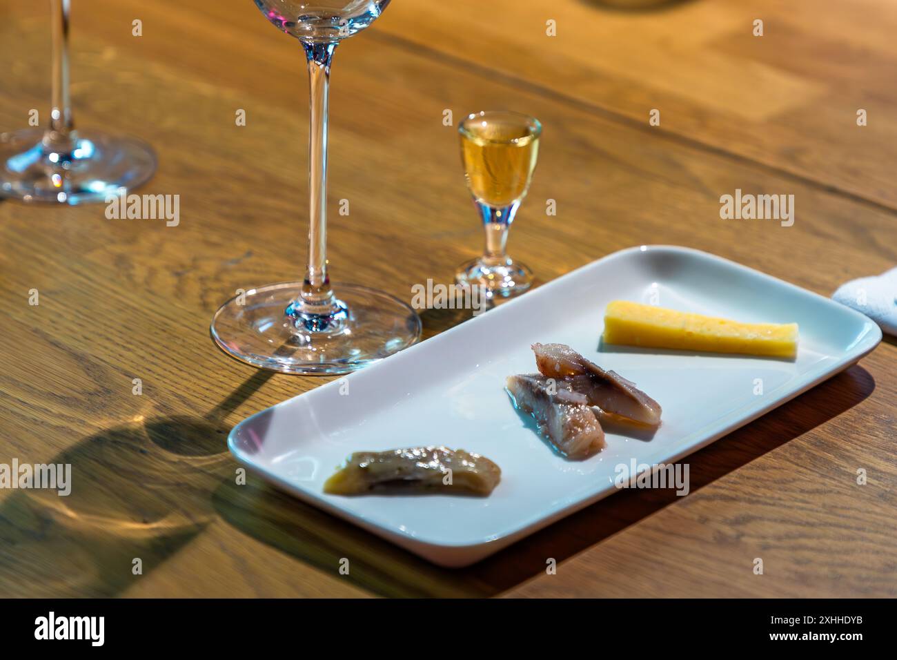 Specialità svedesi, qui aringhe sottaceto e formaggio Västerbotten svedese insieme all'acquavite. Degustazione in un tour gastronomico attraverso Södermalm, Stoccolma. Un bicchiere di Linie Aquavit fa parte degli spuntini svedesi. Bondegatan, Stoccolma, Stockholms län, Svezia Foto Stock