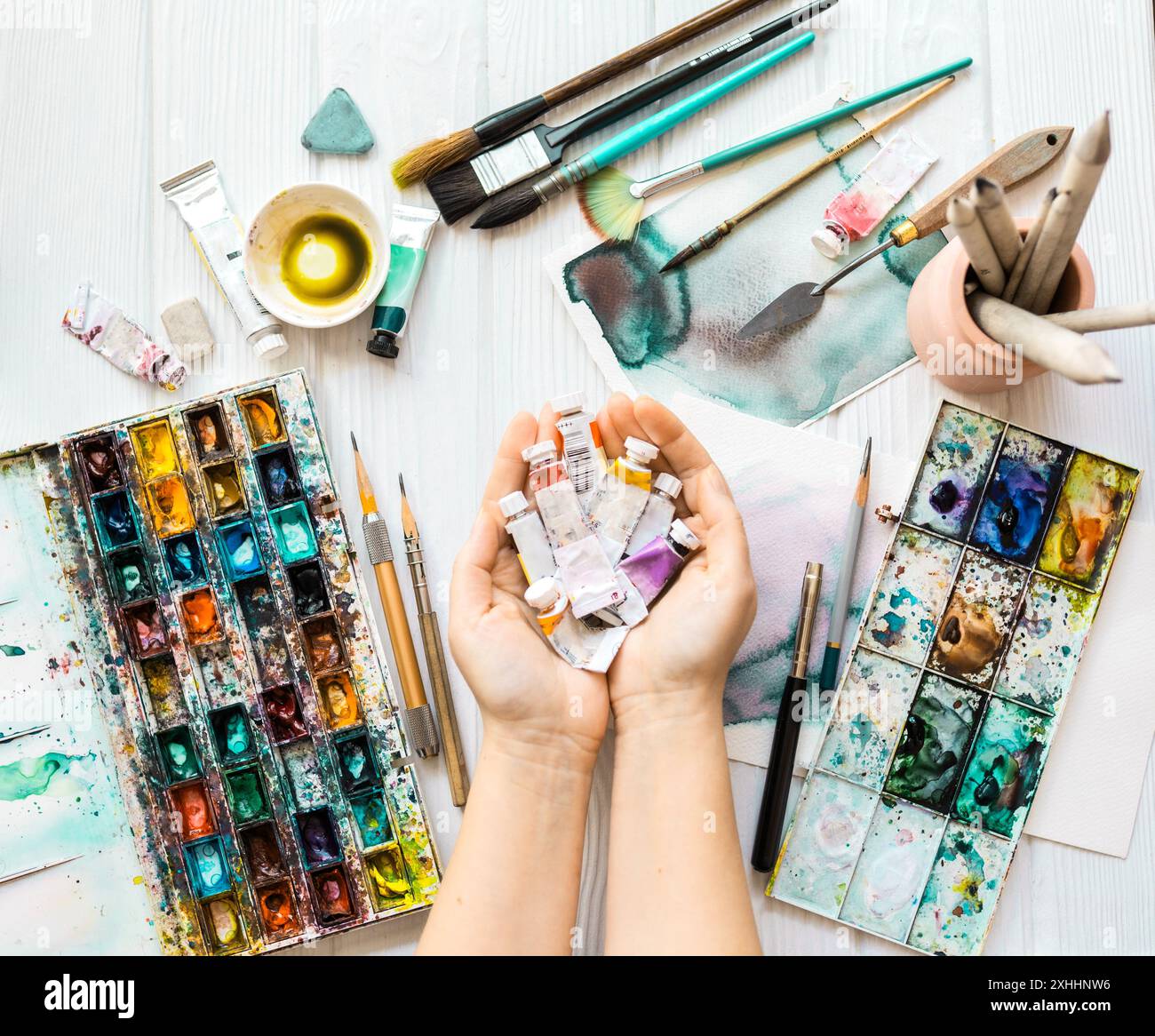 Artista con vista superiore pitture. Lezioni d'arte. Mani con vernici, pennelli, matite e altri strumenti per disegnare. Foto Stock