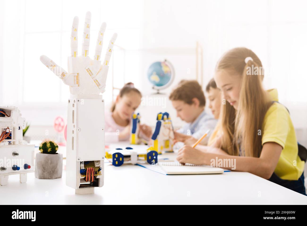 Modello di mano robotizzato in primo piano con i bambini in classe Foto Stock