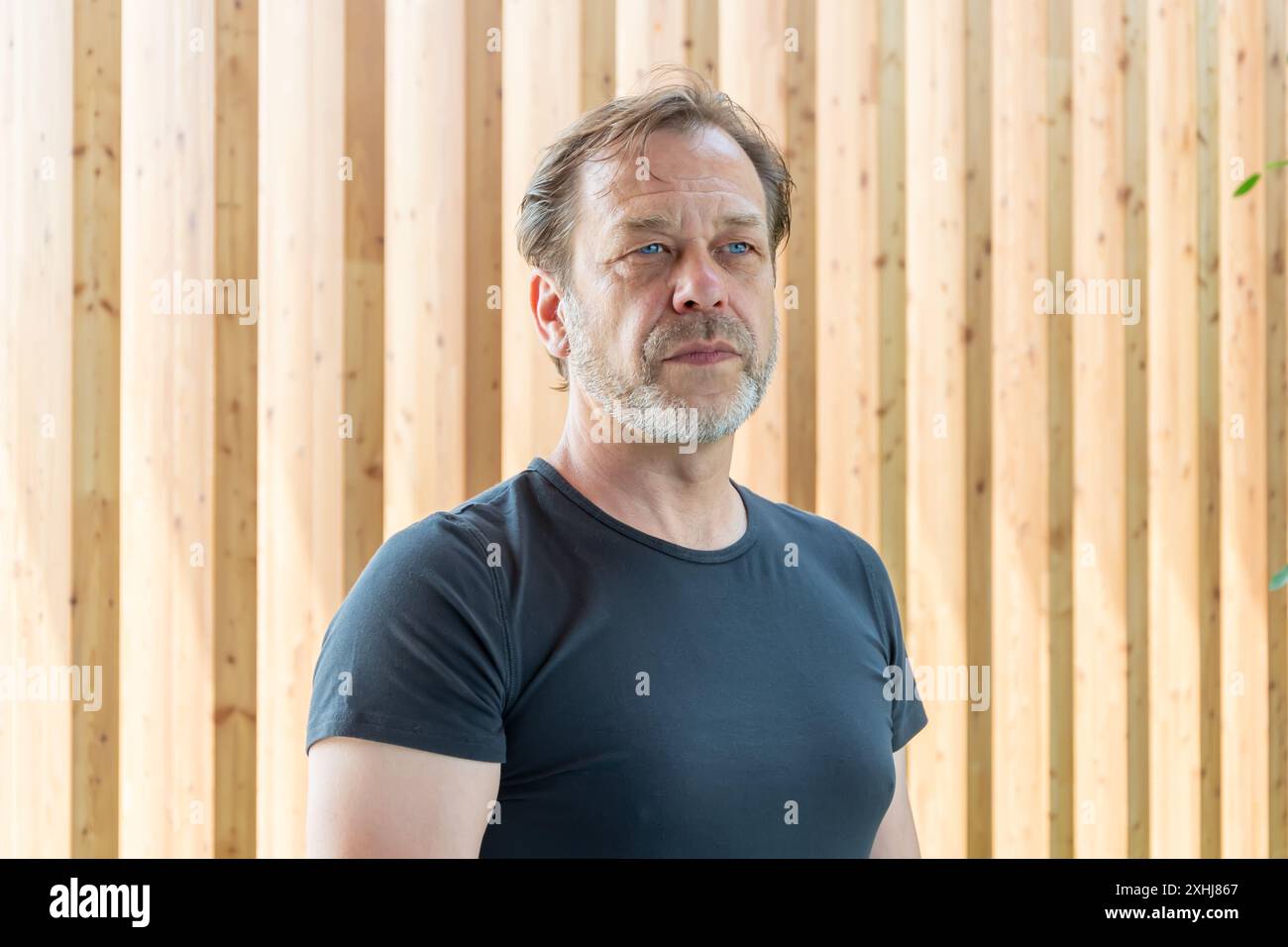 Ritratto di un uomo elegante e barbuto di 50-55 anni su uno sfondo di legno testurizzato. Foto Stock