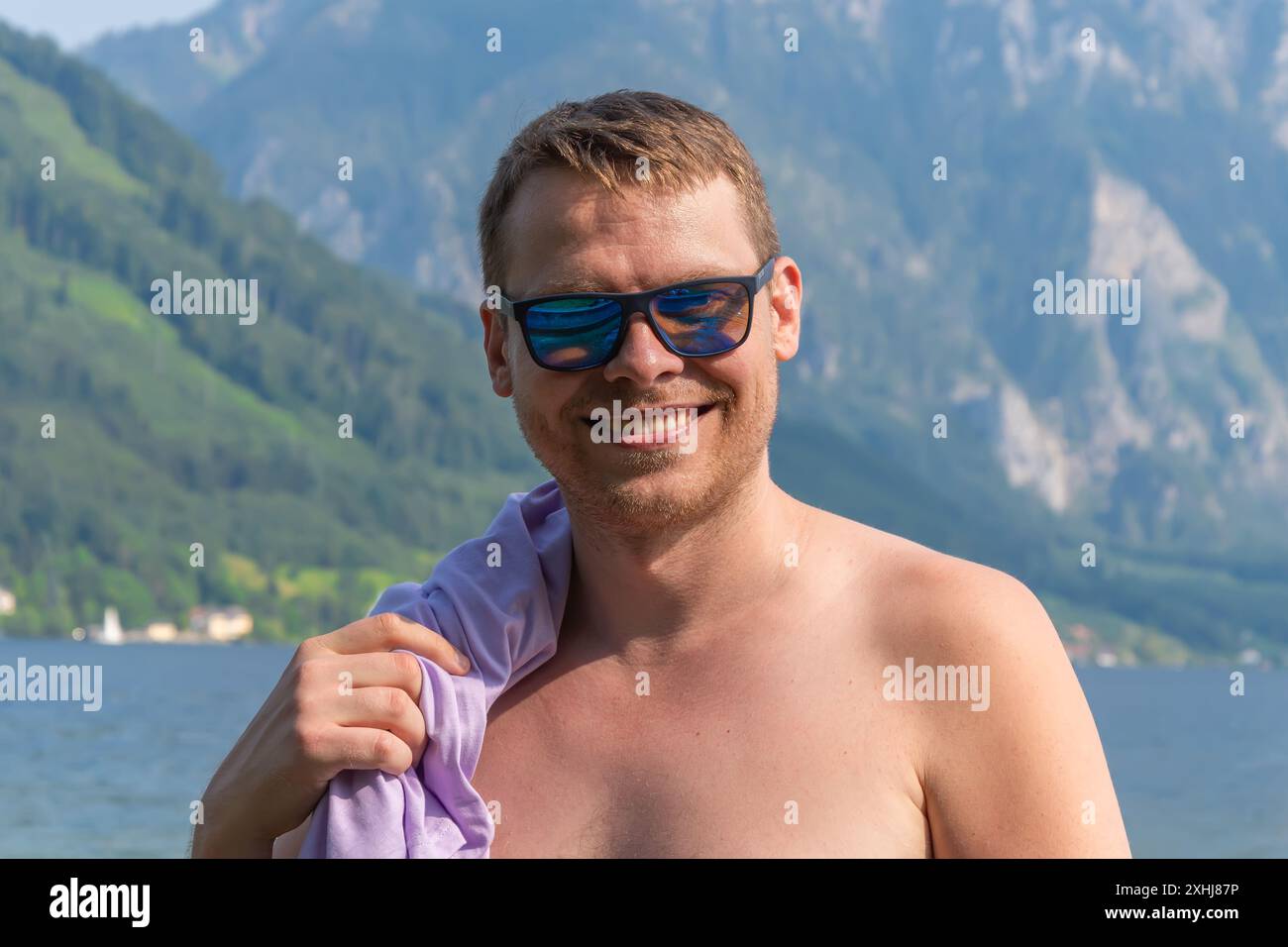 Ritratto di un uomo di 40-45 anni in occhiali da sole sullo sfondo di montagne e acqua. Foto Stock