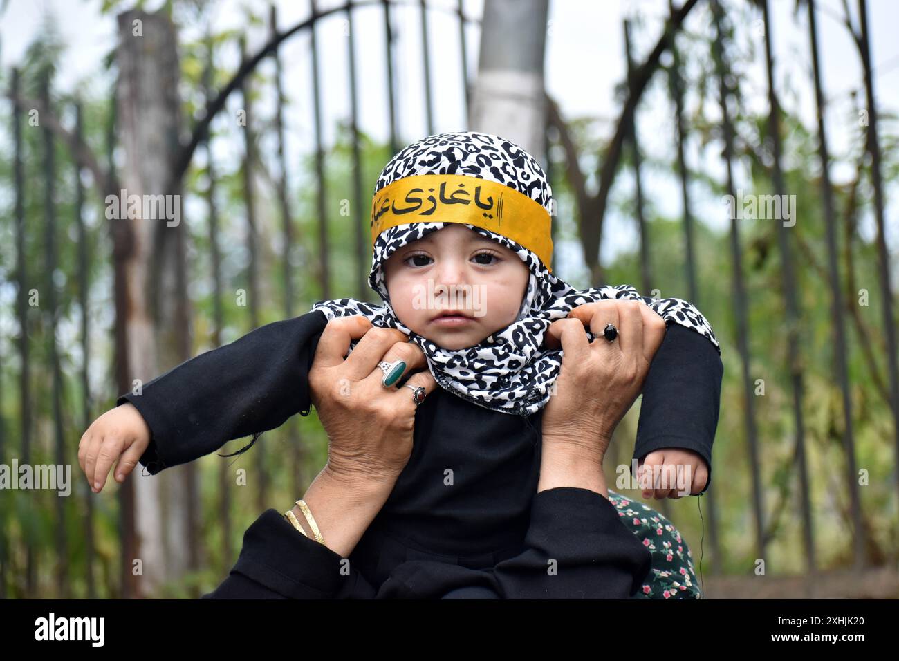 Srinagar, India. 14 luglio 2024. Una ragazza musulmana sciita del Kashmir portata da una donna (non in cornice) durante una processione di Muharram il settimo giorno di Muharram a Rainawari Srinagar il 14 luglio 2024. Muharram è il primo mese del calendario lunare islamico ed è considerato uno dei mesi più sacri dell'Islam. (Foto di Danish Showkat/Sipa USA) credito: SIPA USA/Alamy Live News Foto Stock