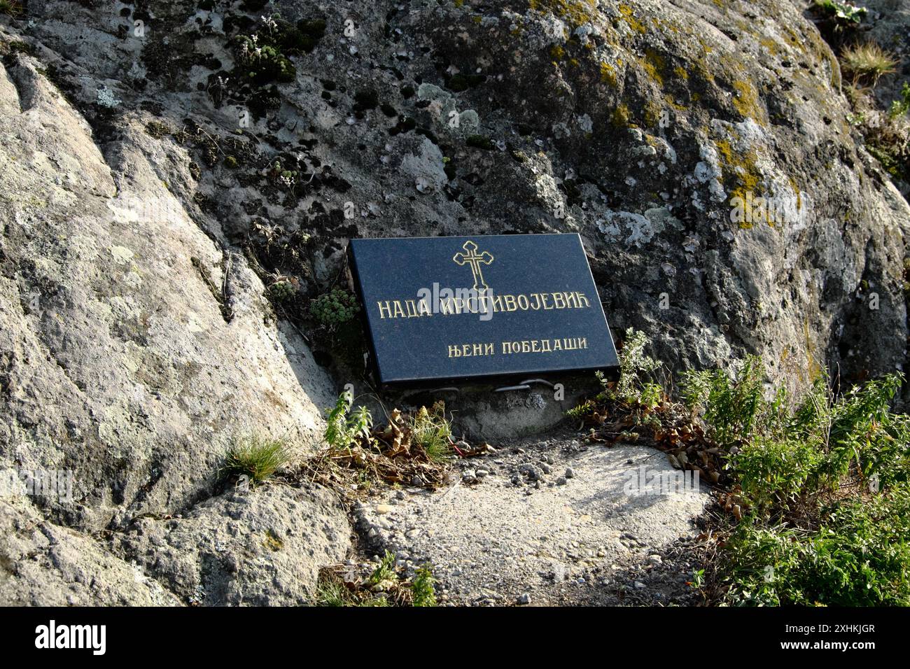 Una targa nera con testo in caratteri cirillici e una croce ortodossa sulla via ferrata per la collina di Ostrvica sul monte Rudnik nella Serbia centrale Foto Stock