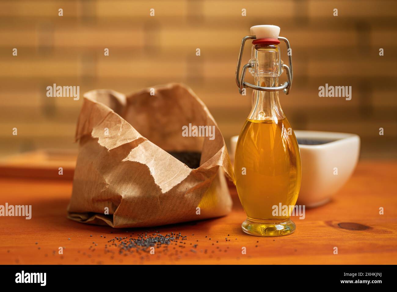 Olio di semi di papavero commestibile o olio di semi di papavero con alcuni semi di papavero di oppio secchi sul tavolo da cucina, attenzione selettiva Foto Stock