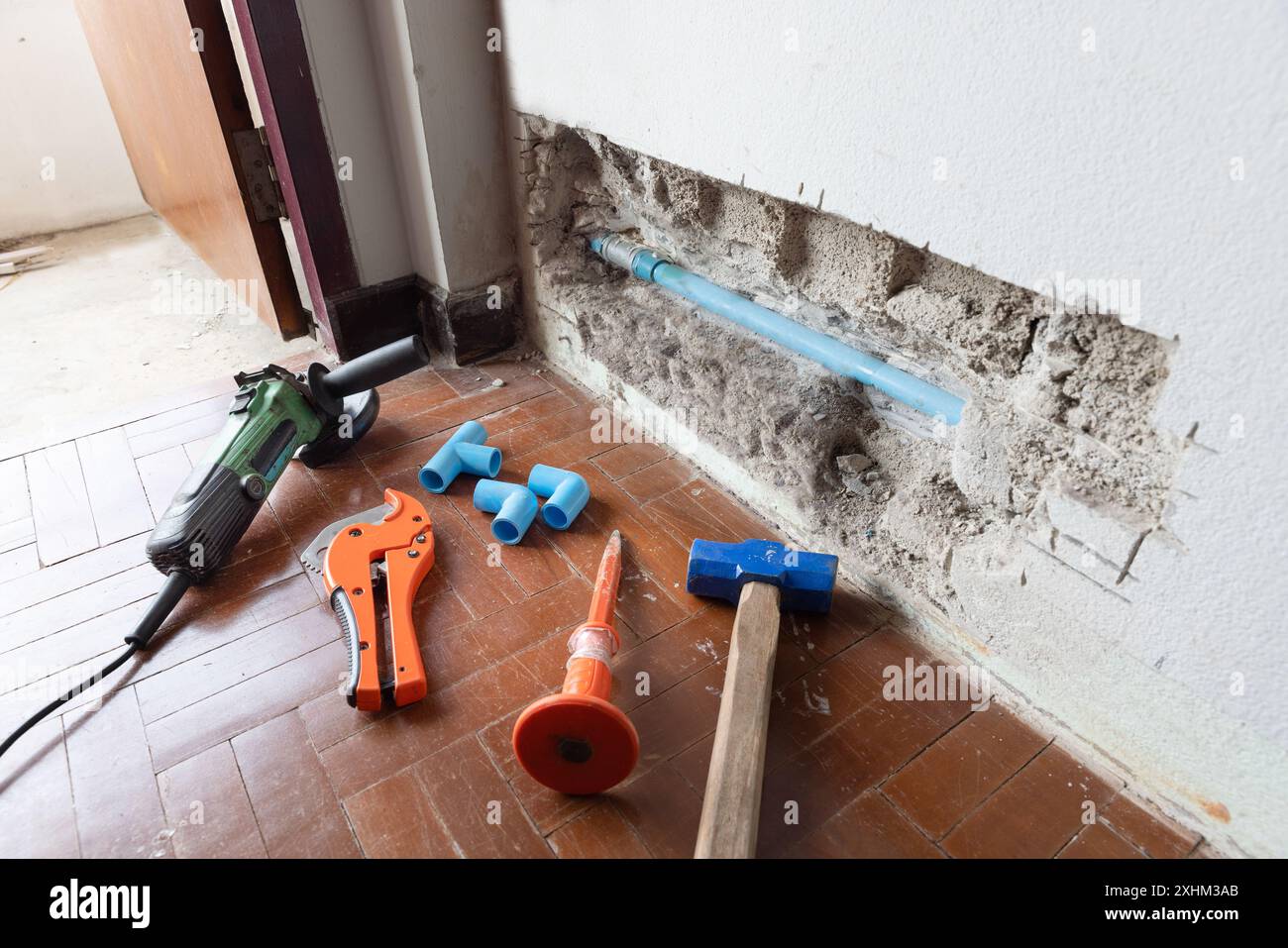 L'idraulico deve aprire una parete per accedere a un tubo rotto. Foto Stock
