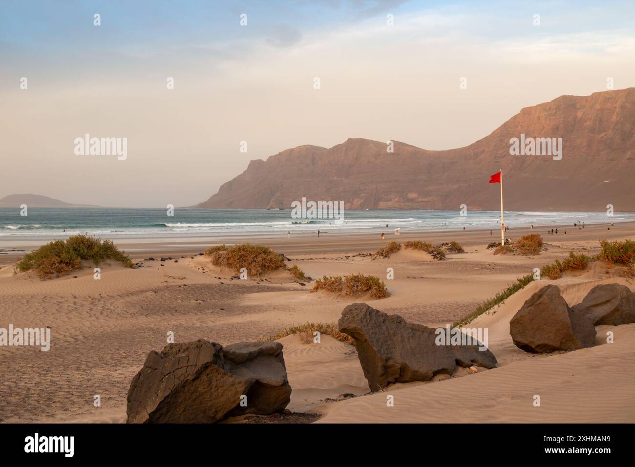 Costa occidentale dell'isola con una spiaggia sabbiosa, popolare per il surf. Golden Hour durante la stagione invernale. Bandiera rossa. Montagne sullo sfondo. Caleta de F. Foto Stock