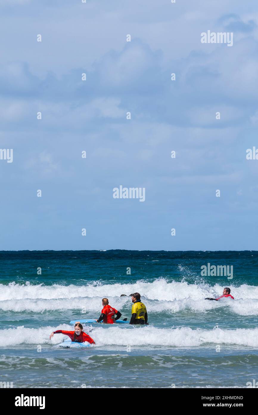 Principianti di surf che tengono una lezione di surf con un istruttore del NQY Activity Centre presso Towan Beach a Newquay in Cornovaglia nel Regno Unito. Foto Stock