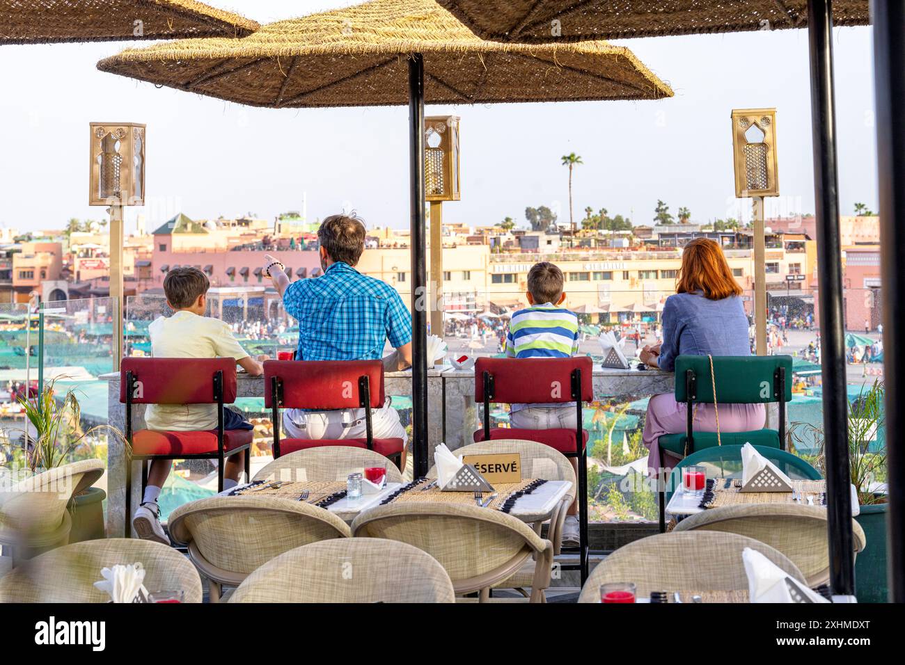 Famiglia felice con due ragazzi che ammirano Marrakesh seduti in uno Sky bar Foto Stock