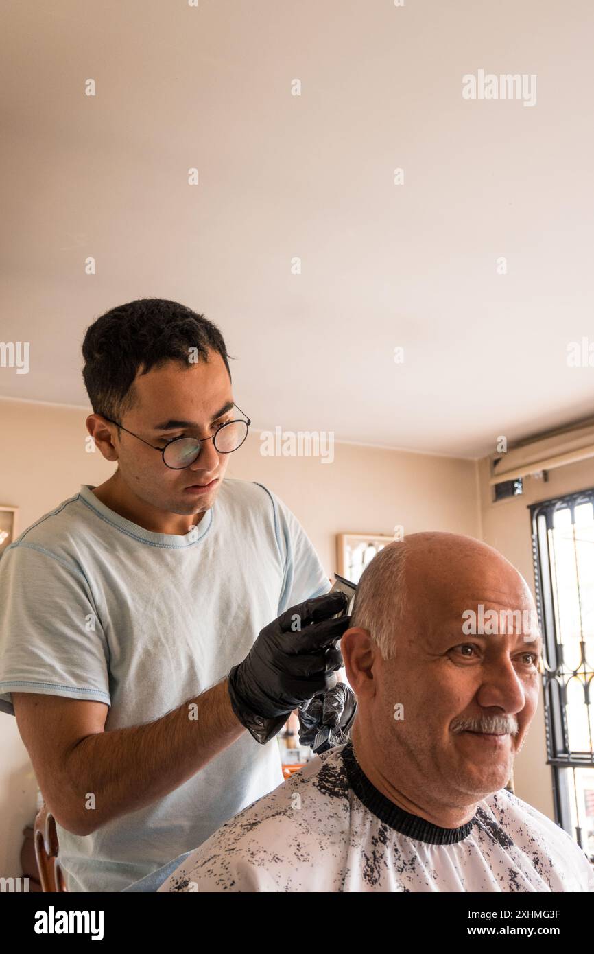 Figlio che taglia i capelli a suo padre a casa Foto Stock