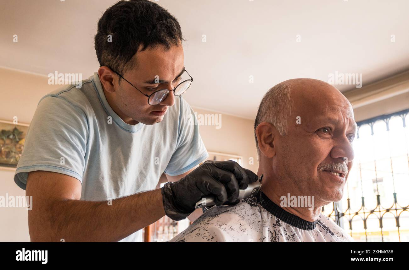 Figlio che taglia i capelli a suo padre a casa Foto Stock