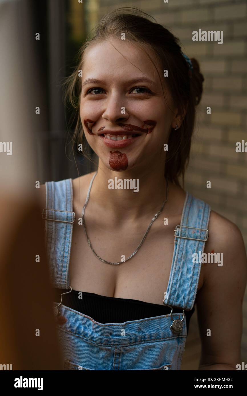 La donna artista le dipinge un baffo sul viso Foto Stock