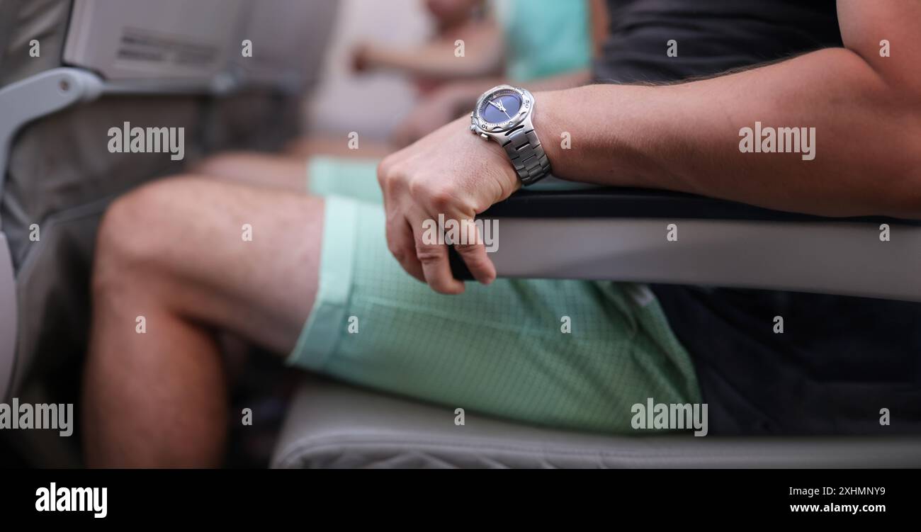 Primo piano di un uomo spaventato afferra con forza il bracciolo in aereo. Aereo e panico. Primo volo e paura di altezze concetto Foto Stock
