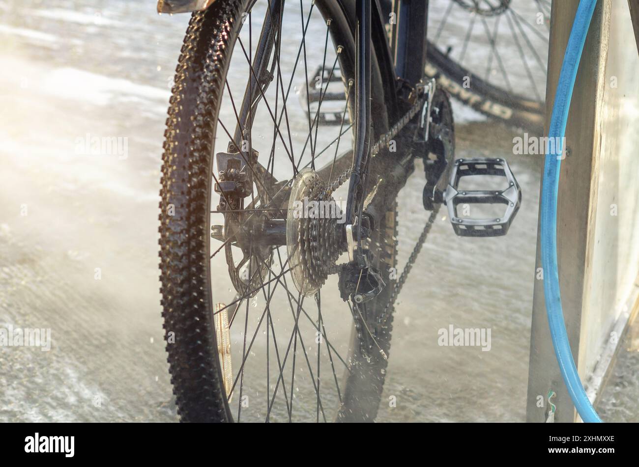 Un potente flusso di acqua lava la bicicletta all'autolavaggio. Pompa ad alta pressione. Manutenzione Foto Stock