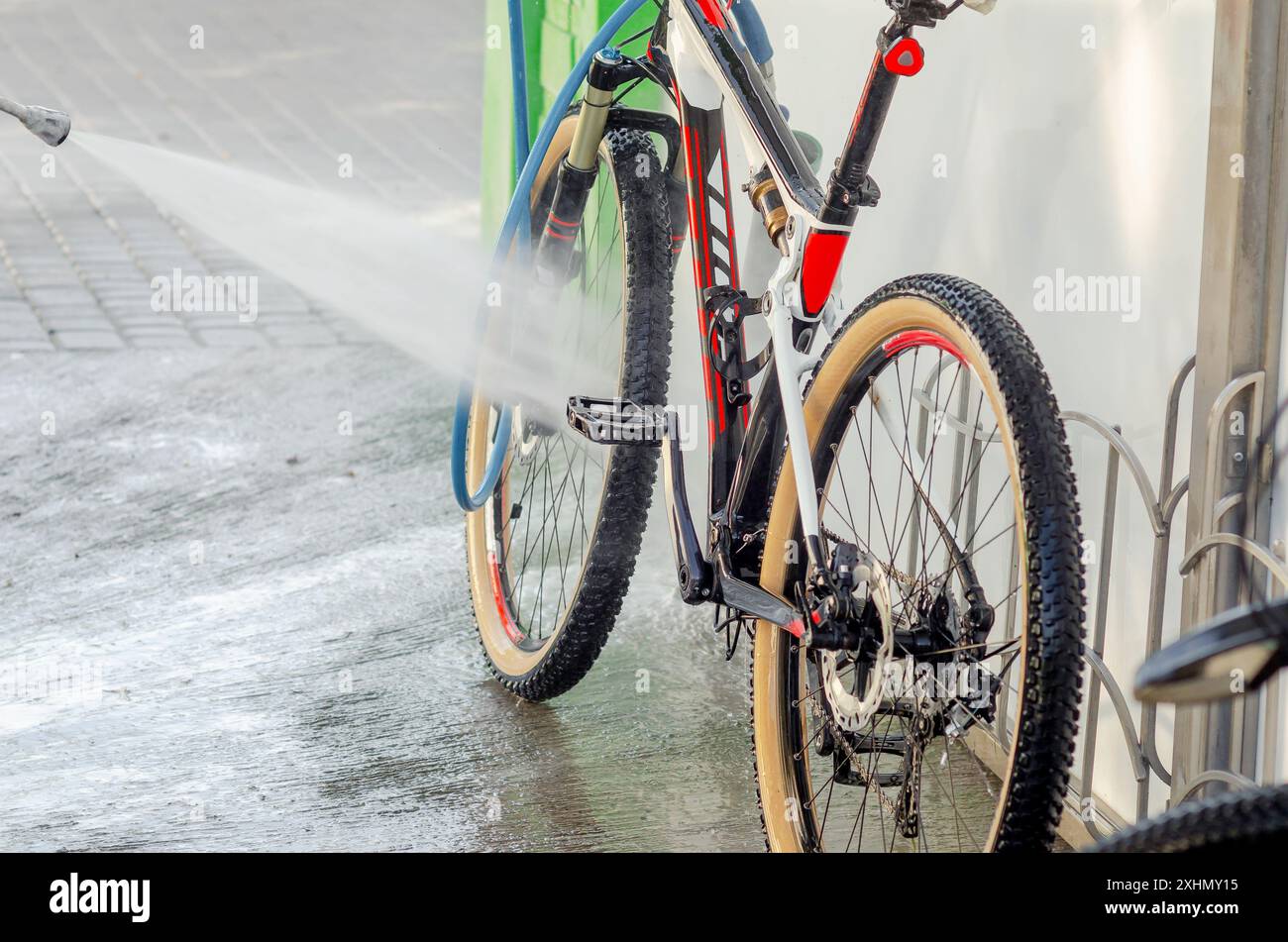 Un potente flusso di acqua lava la bicicletta all'autolavaggio. Pompa ad alta pressione. Manutenzione Foto Stock