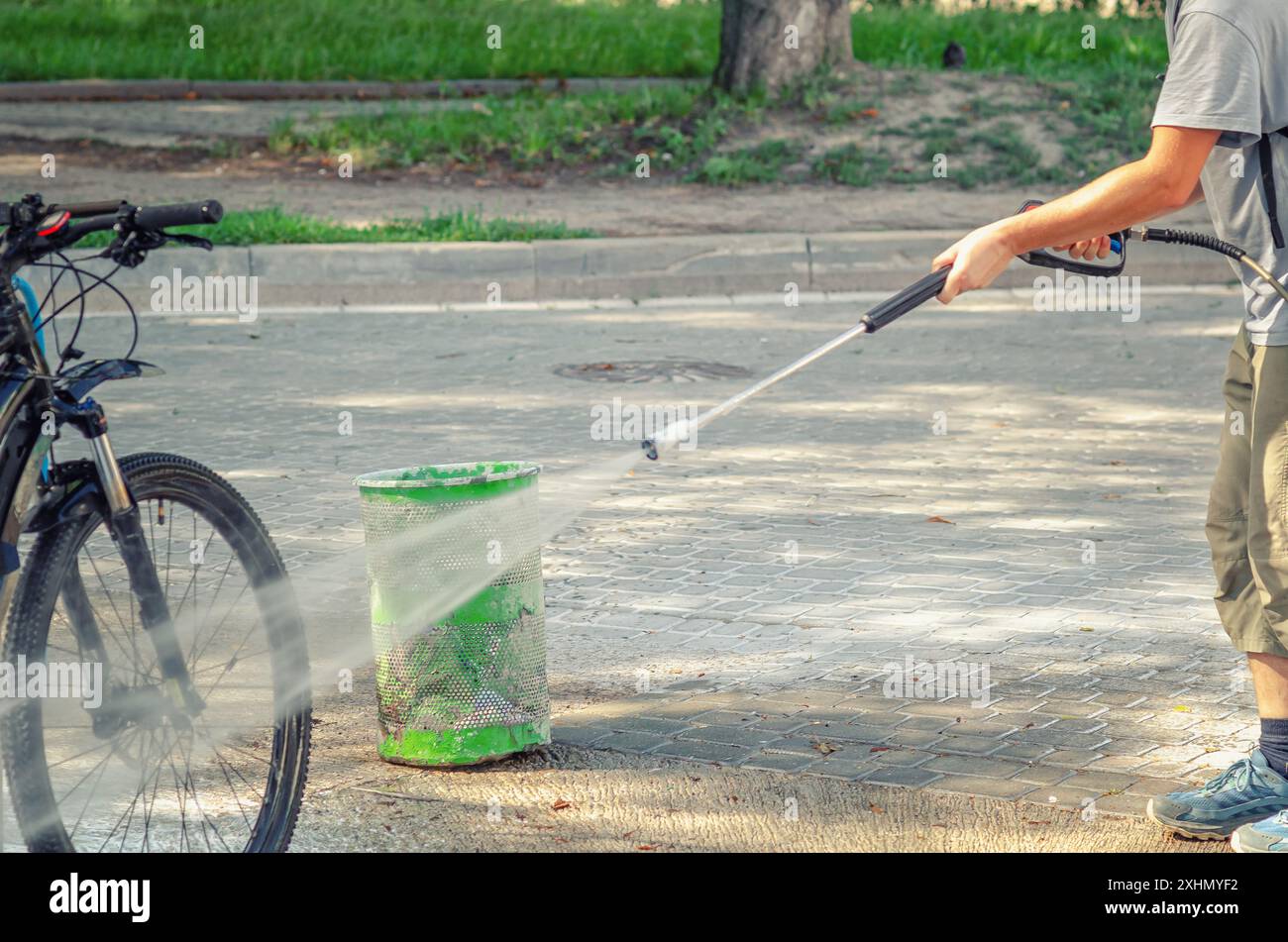 L'uomo lava la bicicletta all'autolavaggio con un potente flusso d'acqua. Pompa ad alta pressione. Manutenzione Foto Stock
