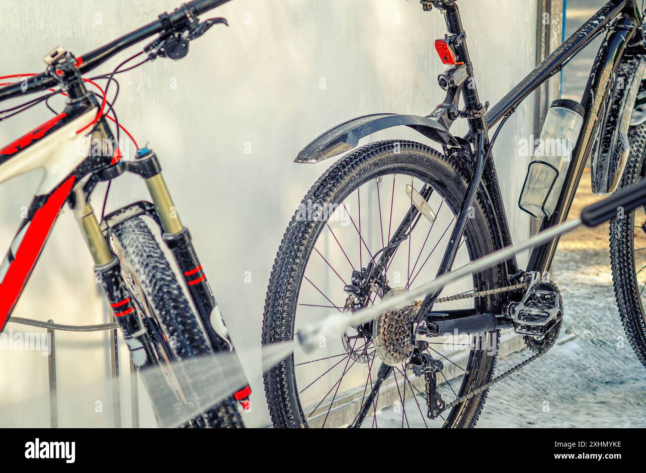 Un potente flusso di acqua lava la bicicletta all'autolavaggio. Pompa ad alta pressione. Manutenzione Foto Stock