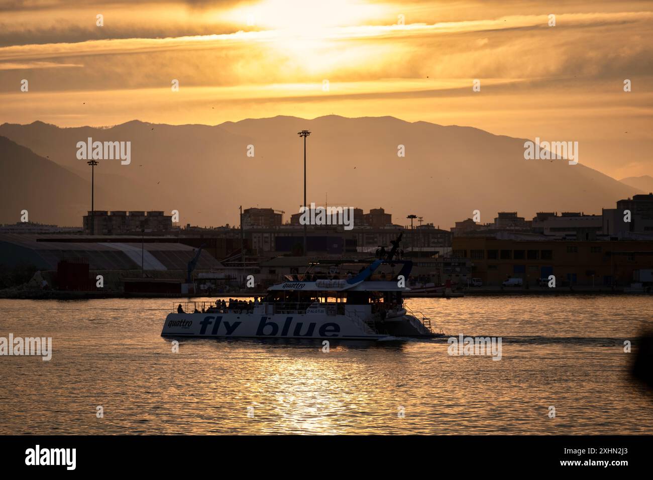 Spagna Malaga tramonto scenario marittimo con barca 'Fly Blue', paesaggio urbano con colori caldi e cielo radioso Foto Stock