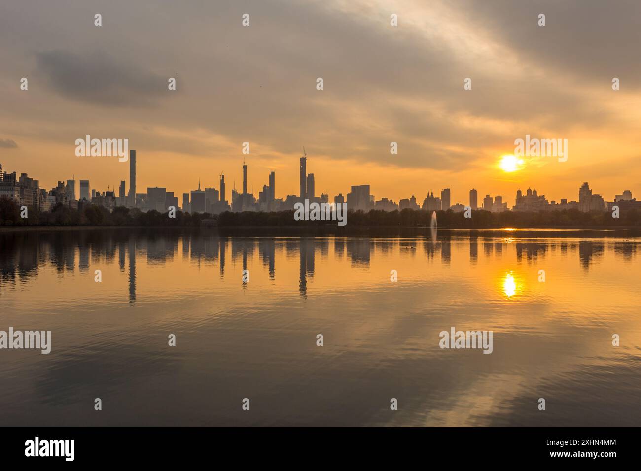 Skyline di Manhattan e riflesso nel lago artificiale Jacqueline Kennedy Onassis a Central Park al Sunny Sunset. New York Foto Stock