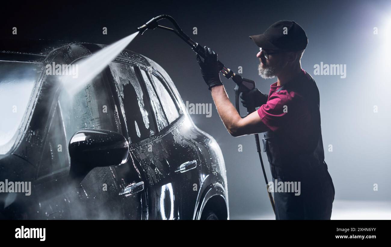 Il nuovissimo veicolo elettrico di una linea di produzione viene pulito con un pulitore ad alta pressione. SUV fresco di fabbrica in un autolavaggio di dettaglio prima di essere lavato e rivestito in ceramica per la protezione Foto Stock