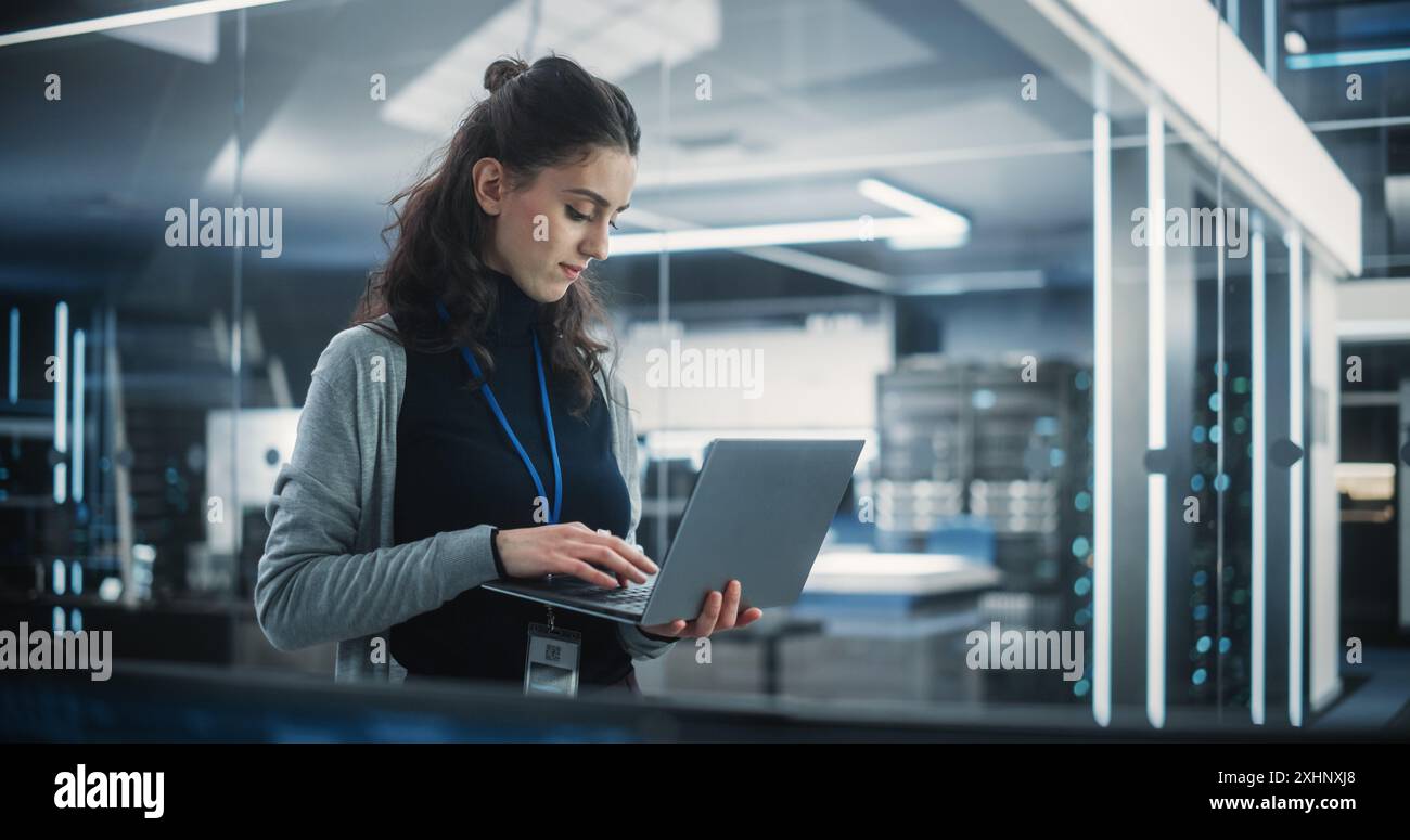 Responsabile del dipartimento di ingegneria del software tecnologico che utilizza un computer portatile. Donna multietnica che guarda a distanza e pensa mentre lavora in ufficio Foto Stock