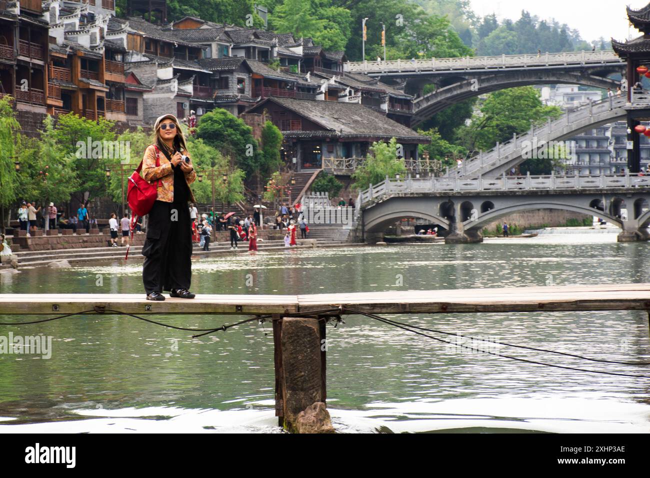 Le donne thailandesi che viaggiano visitano utilizzano la fotocamera per scattare foto al paesaggio del fiume tuojiang e agli edifici storici, architettura storica dell'antica Xiangxi Phoenix Foto Stock