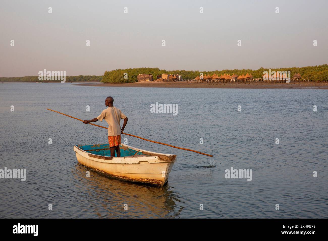 Senegal, il delta di Saloum dichiarato patrimonio mondiale dall'UNESCO, Fadiouth o isola di molluschi, pescatore che avanza la sua barca con una lunga canna di bambù sulla riv Foto Stock