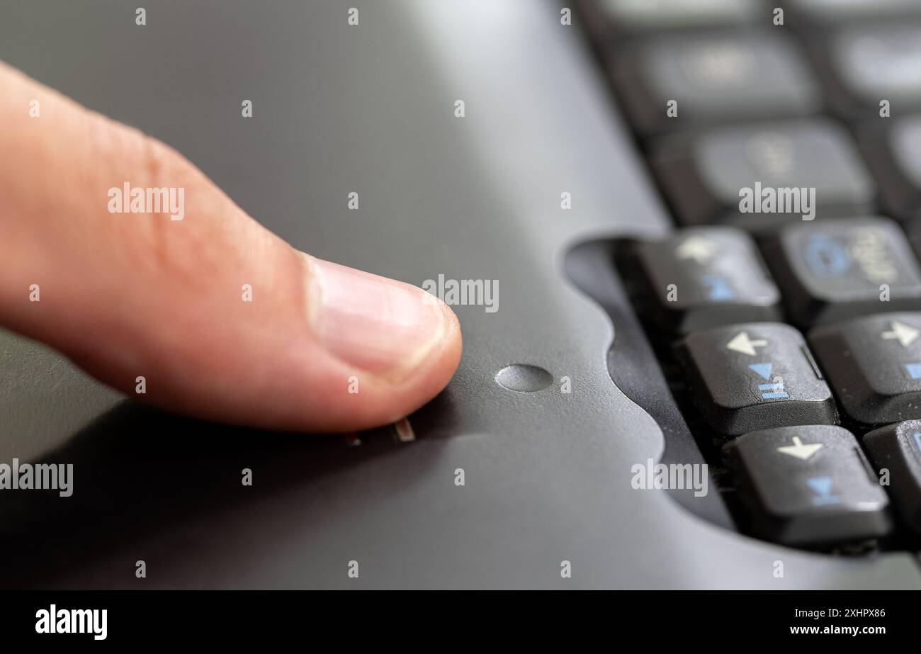 Uomo che utilizza un modulo scanner di impronte digitali integrato in un computer portatile, che fa scorrere le dita sul dettaglio del sensore di impronte digitali in primo piano, una sola persona. Autenticazione biometrica Foto Stock