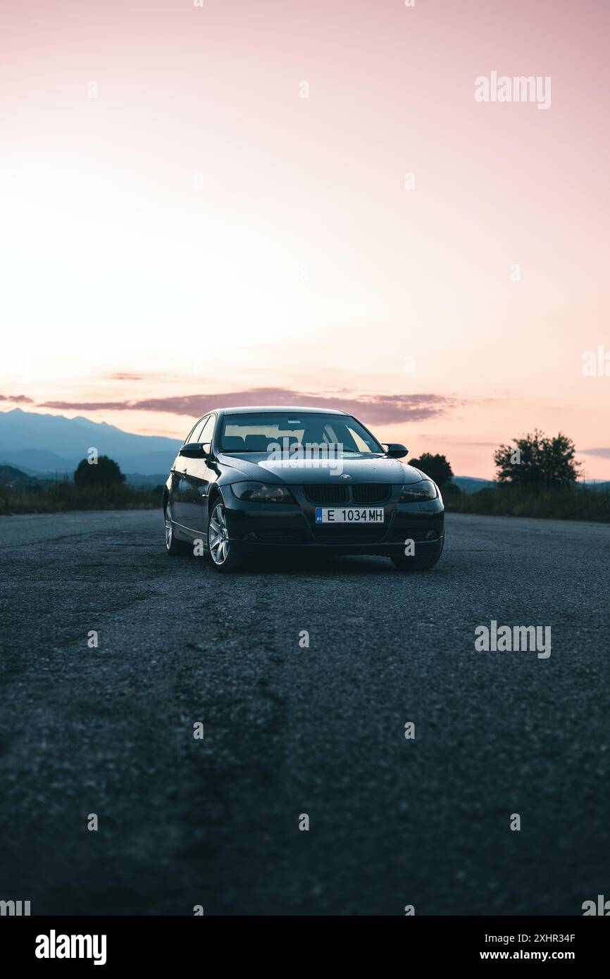 Bulgaria - 07 23 2024: Epica foto al tramonto di una BMW E90 in un aeroporto vuoto con sfondo colorato. Foto Stock