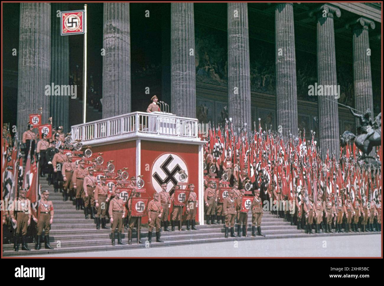 DISCORSO DI GOEBBELS il leader della Propaganda nazista degli anni '1930 Joseph Goebbels in uniforme che tiene un discorso su un podio decorato con la Swastika al Lustgarden di Berlino, con le truppe di Sturmabteilung in piedi con una moltitudine di bandiere di Swastika (immagine a colori rara) nella Germania nazista Foto Stock