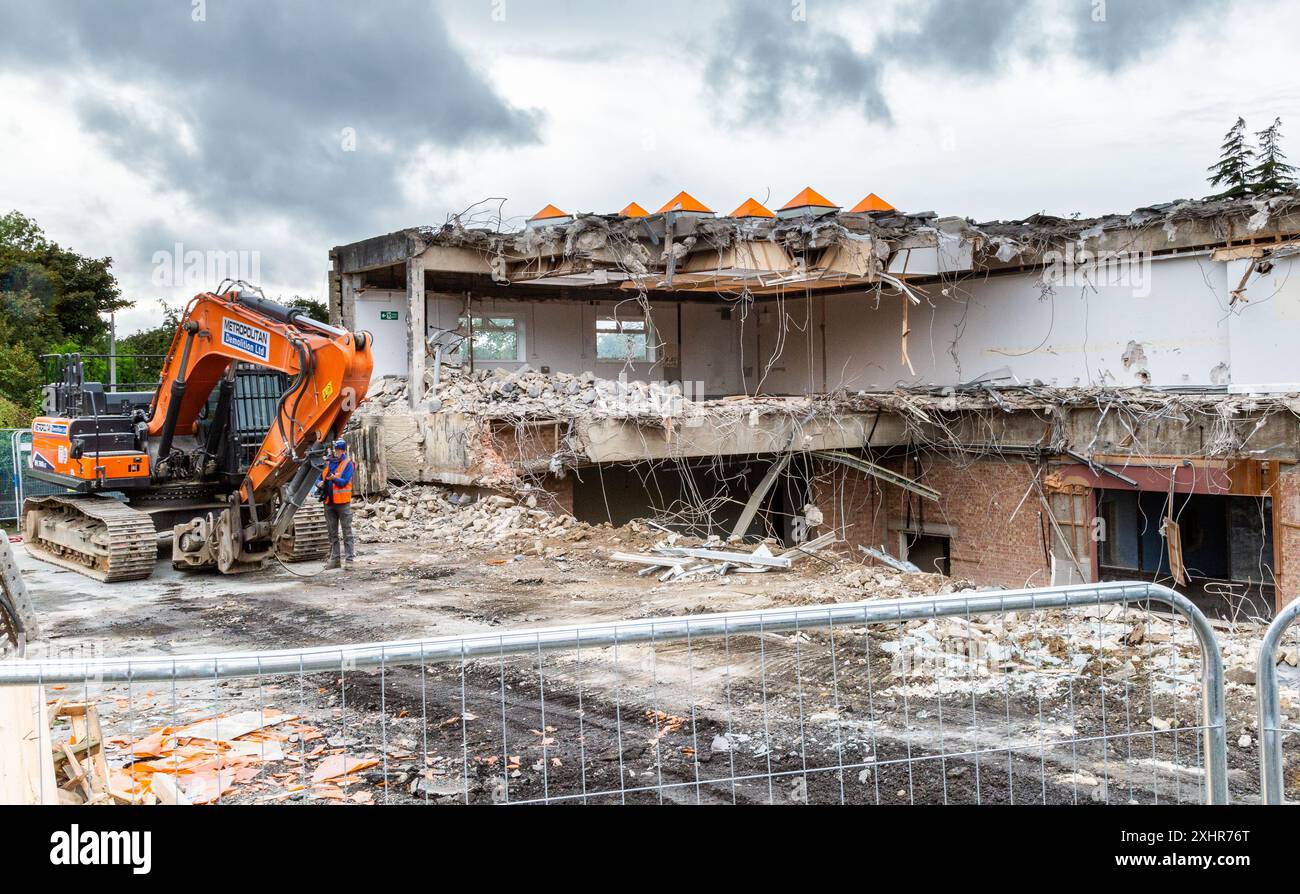 Un escavatore per demolizione al lavoro nel processo di demolizione (demolizione) Baildon Library e Ian Clough Hall (Bradford Council Buildings). Foto Stock